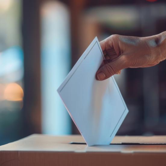 Person, der putter et stykke papir ned i en lukket kasse - de stemmer til valg.