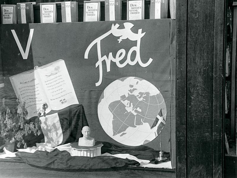 Foto i sort/hvid af et skilt med en jordklode, med teksten "Fred" over.